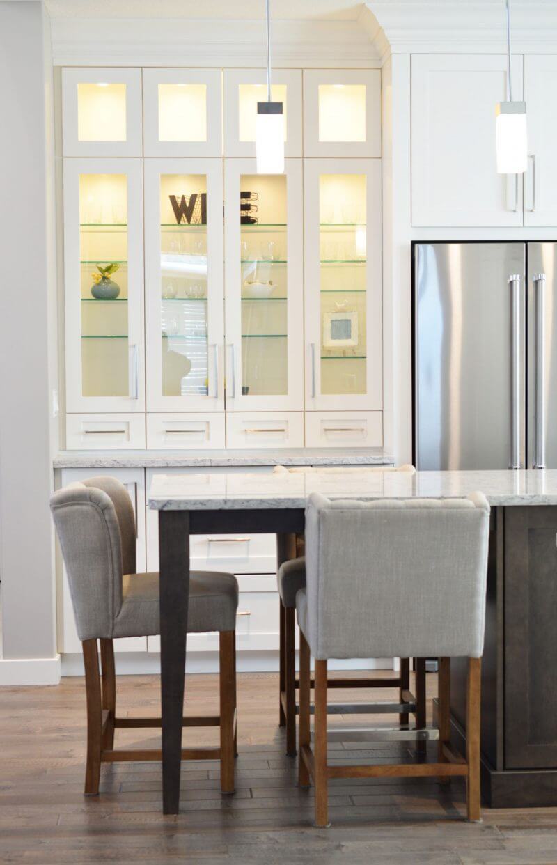 Breakfast bar with hanging pendant lights and sideboard with lit-up backdrop.