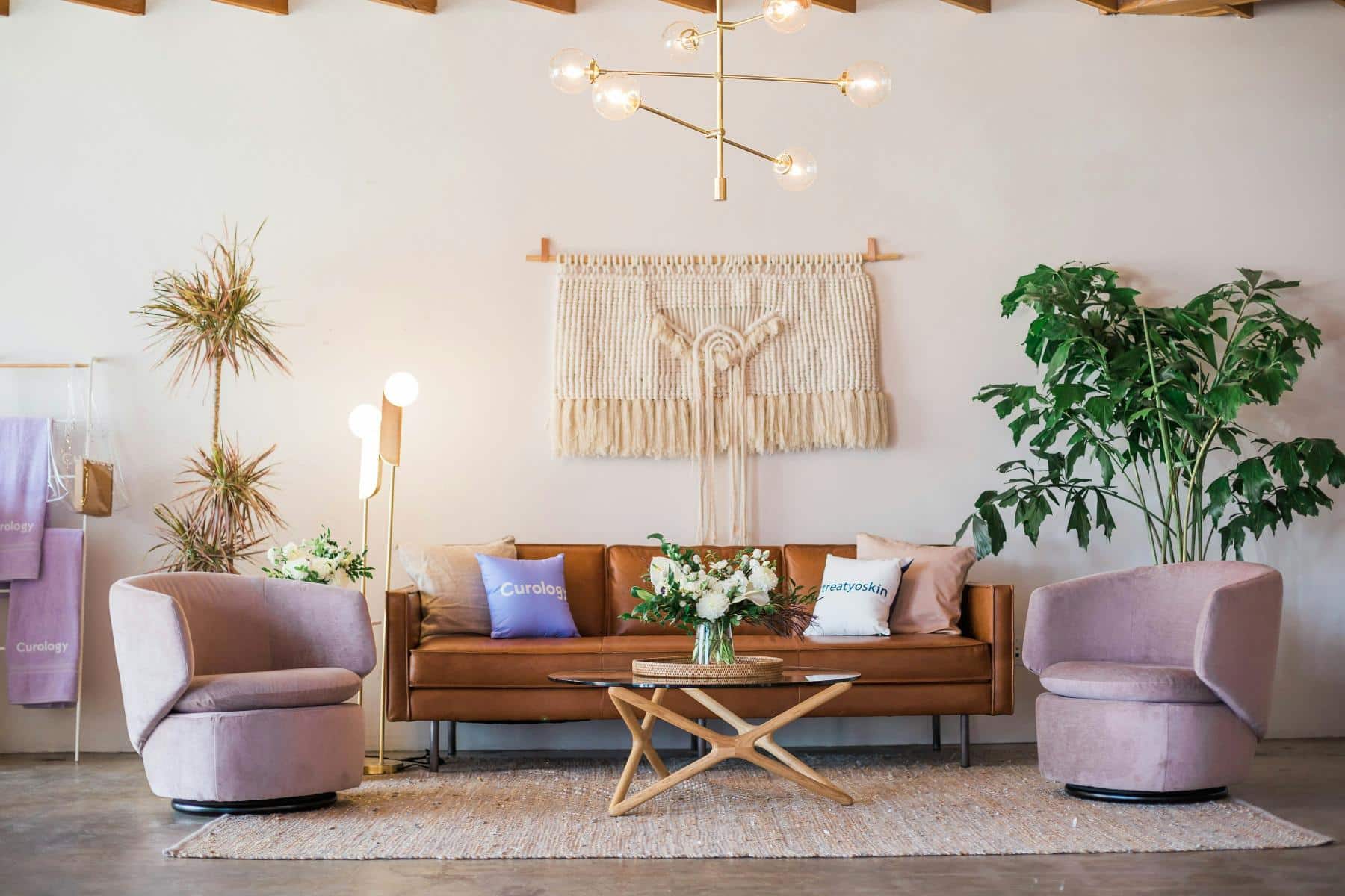 A boho style living room with a terracotta coloured sofa and a large macrame wall hanging