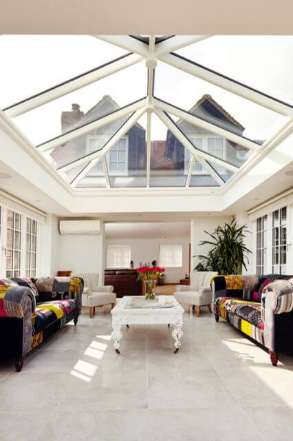A conservatory with colourful sofas and glass roof