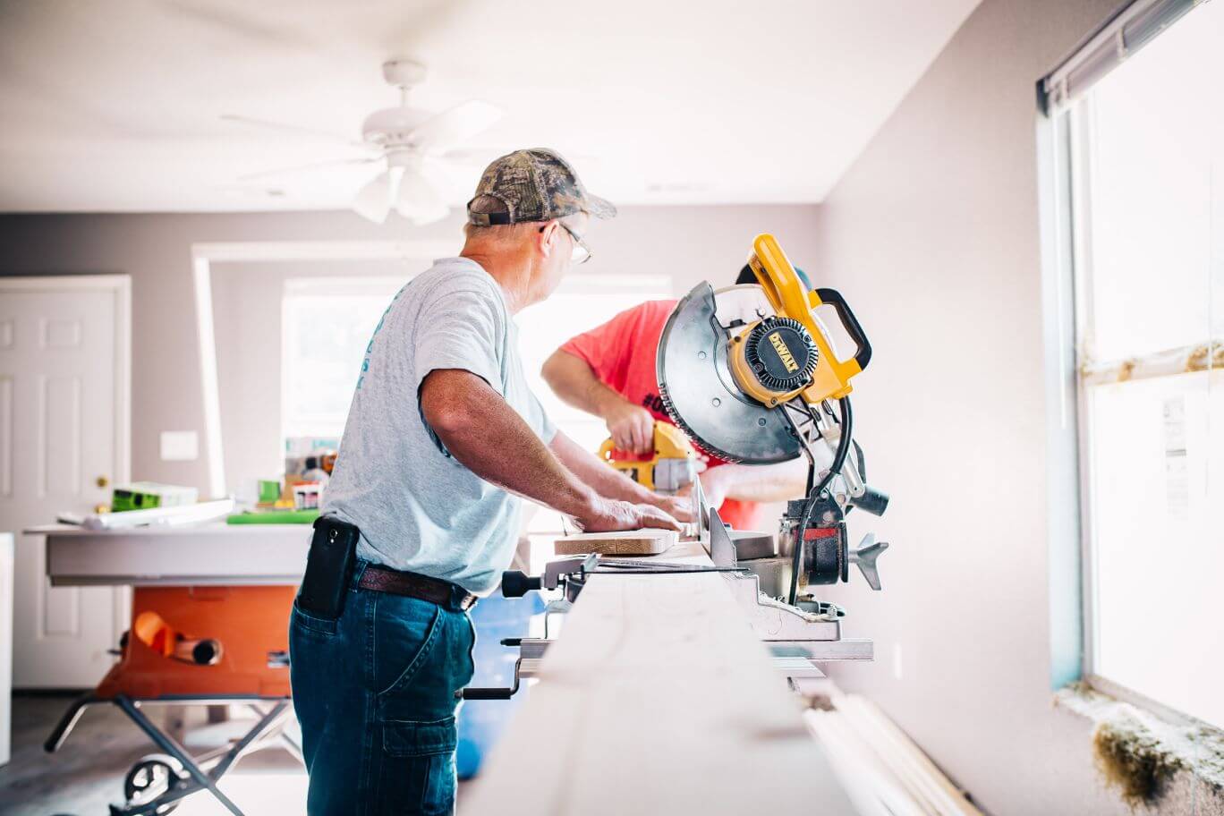 Two tradesmen using power tools to cut wood down in a new build house
