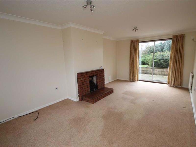The lounge in the new house with cream carpet and cream walls with a brick fireplace