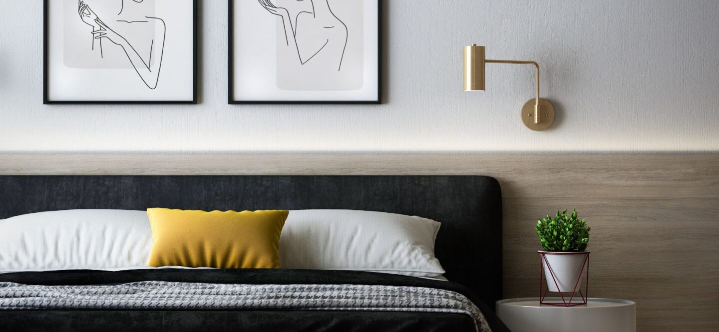 Black bed with a modern gold bedside light on the wall
