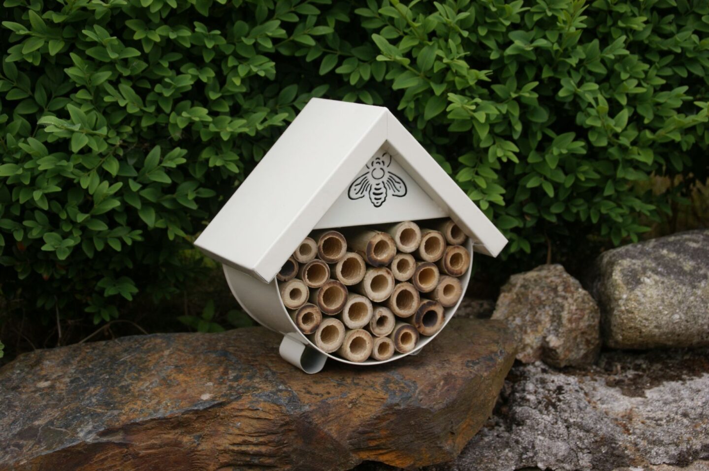 A bee house on a wall in a garden to encourage the bees