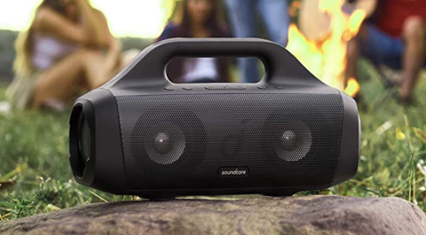 Bluetooth speakers placed on a rock next to a bonfire