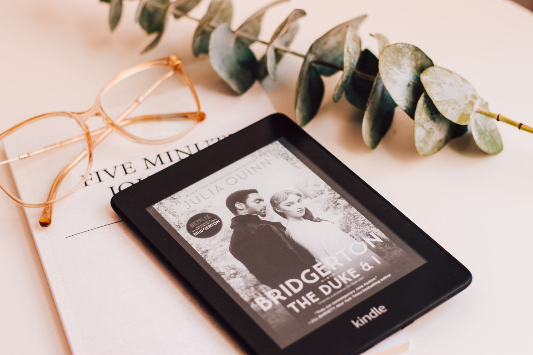 The Bridgerton book series on Kindle on a surface with eucalyptus