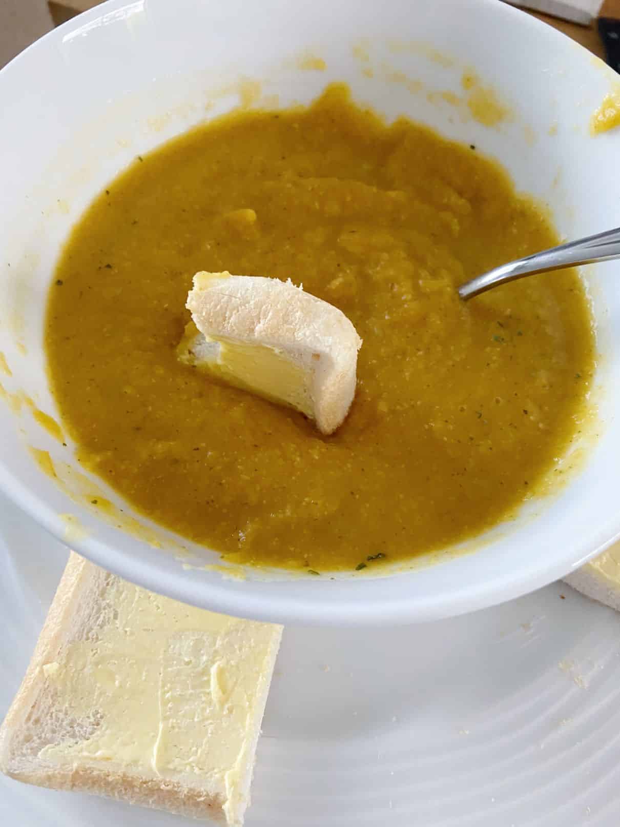 A piece of bread in the butternut squash soup
