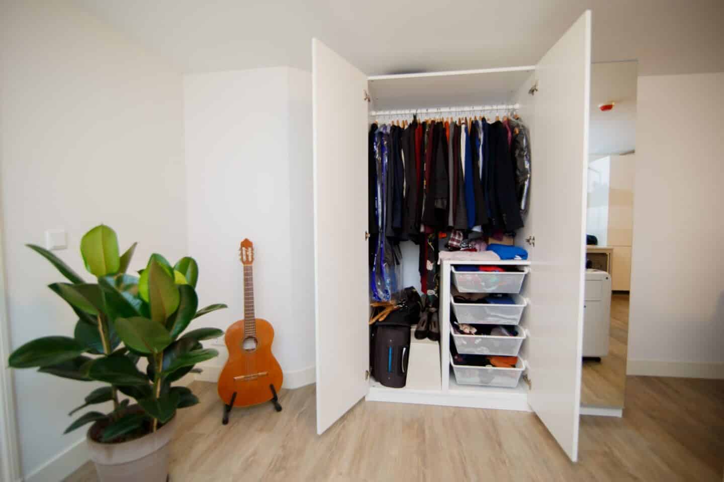An organised wardrobe with hanging clothes and drawer space