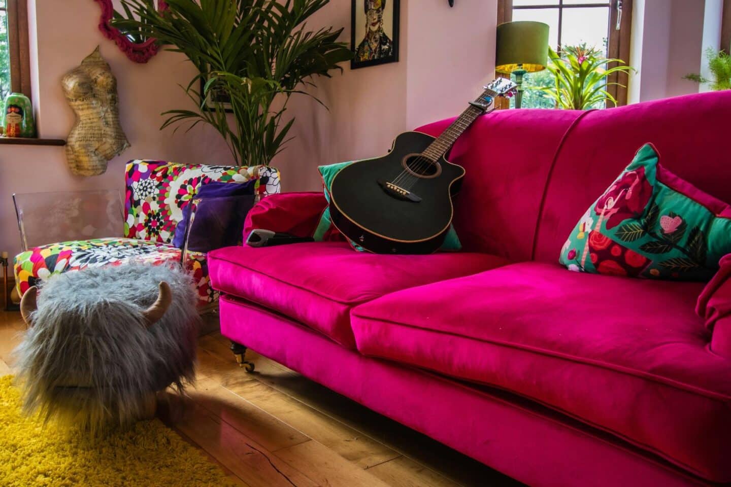 A bright pink sofa in a modern living room with wooden floors