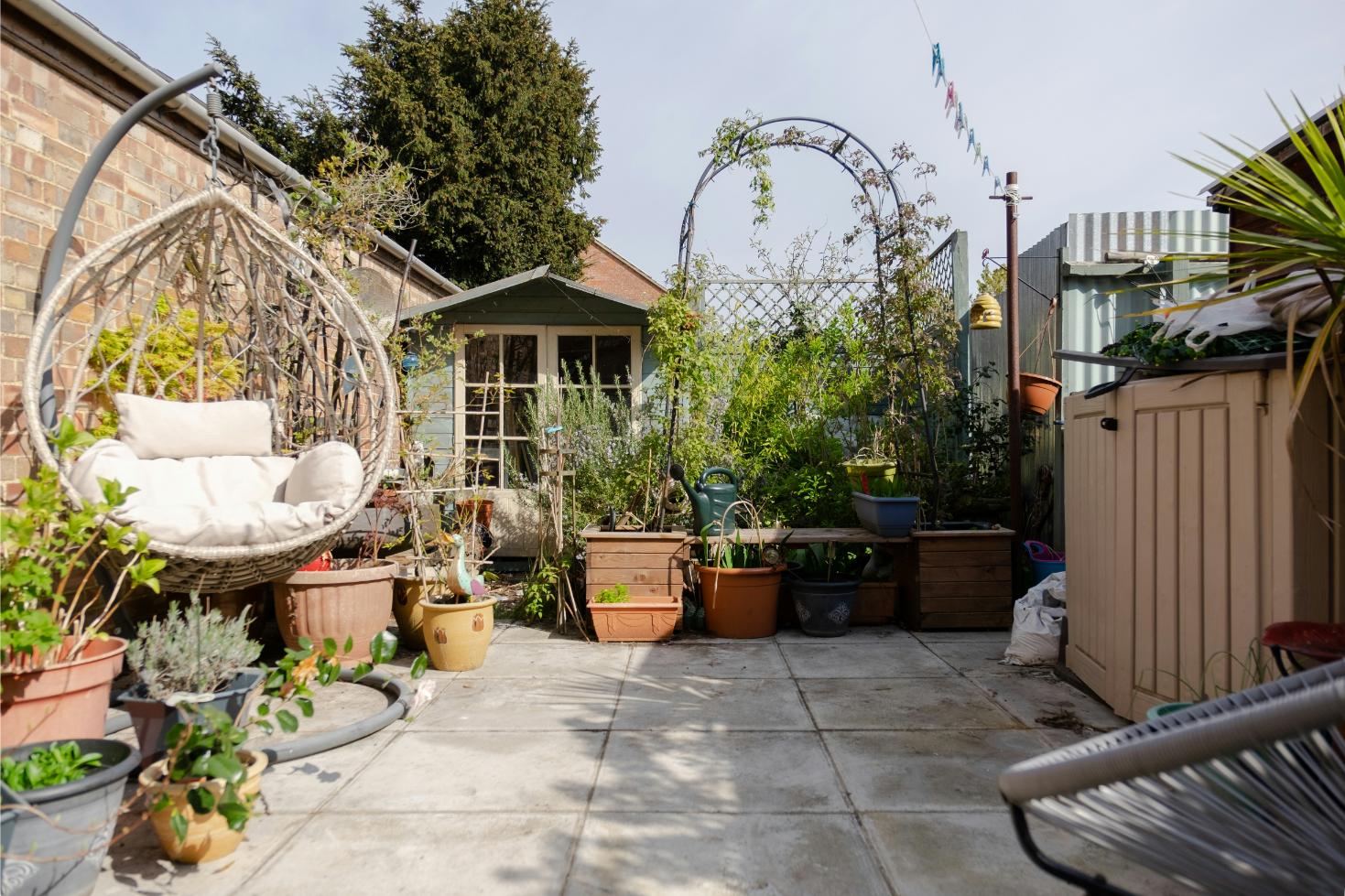 A garden with a hanging egg chair outside