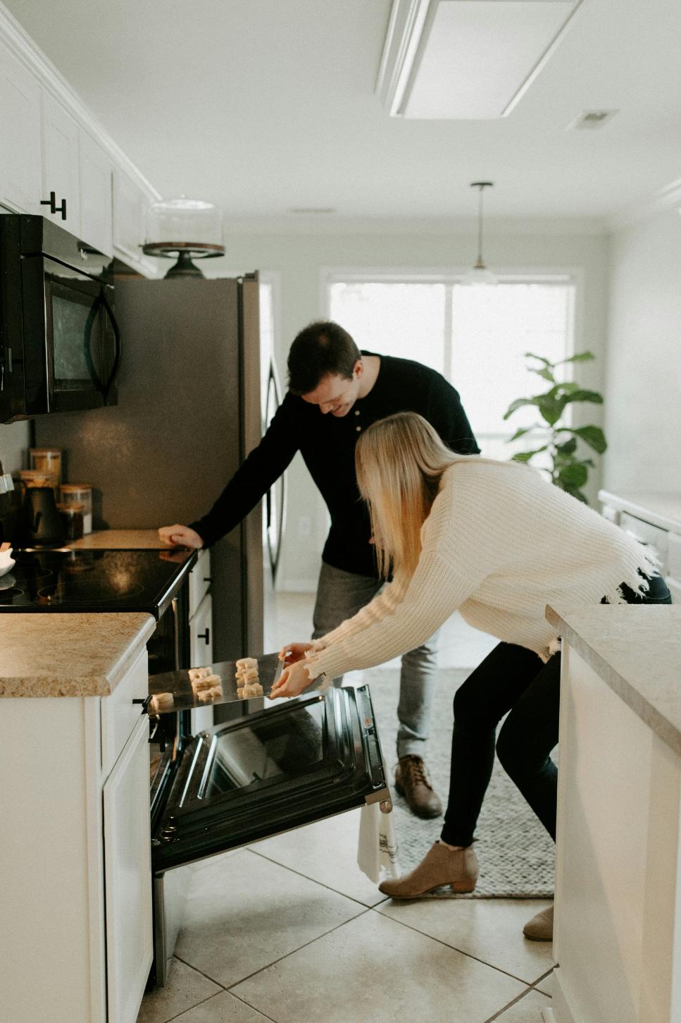 A couple taking some Christmas cookies out of the oven