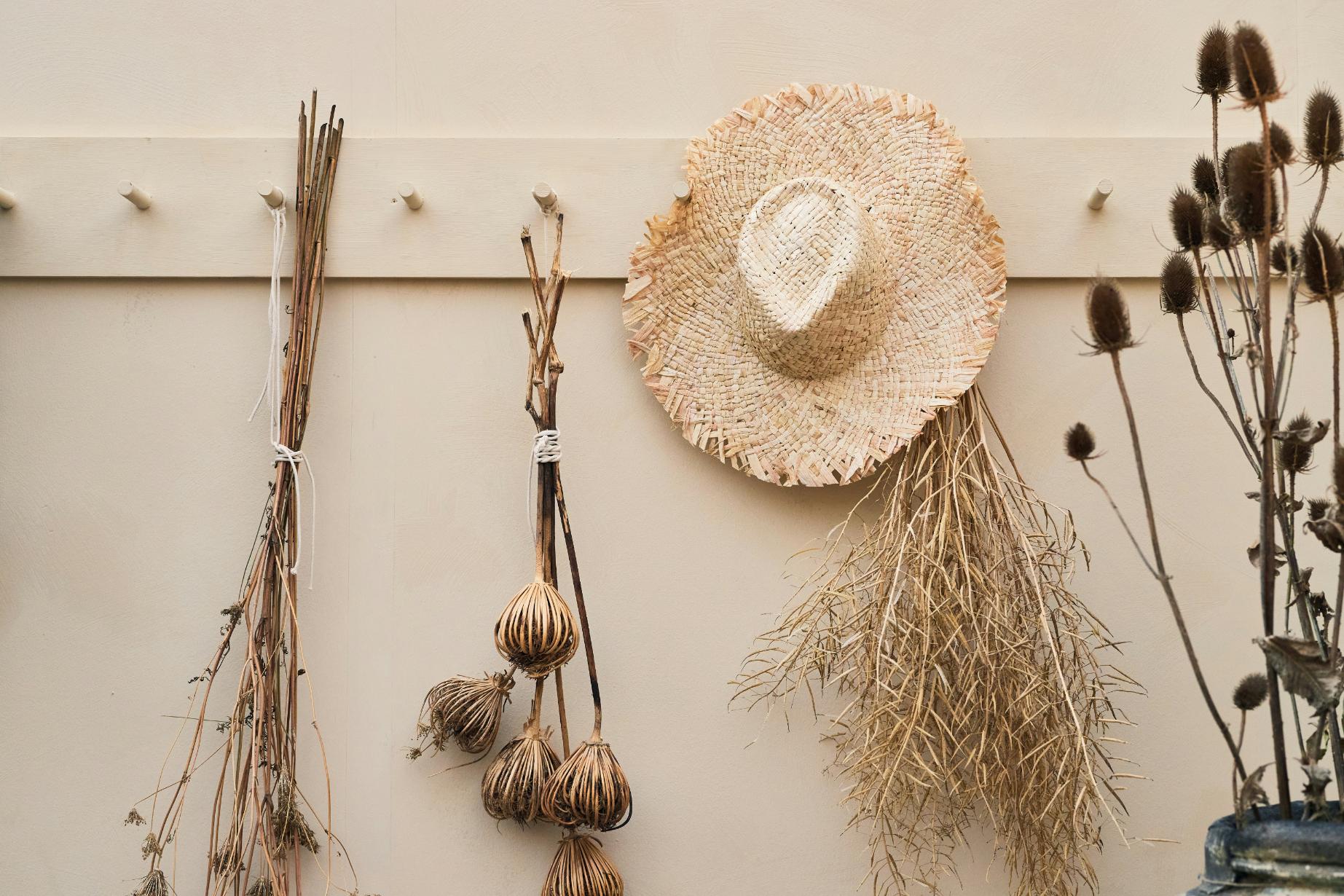 Dried flowers hanging from a coat rack with a hat next to them
