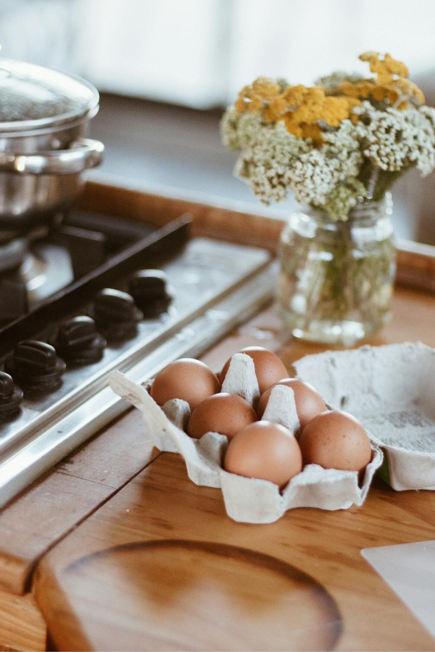 A carton of eggs next to a hob on a wooden kitchen worktop
