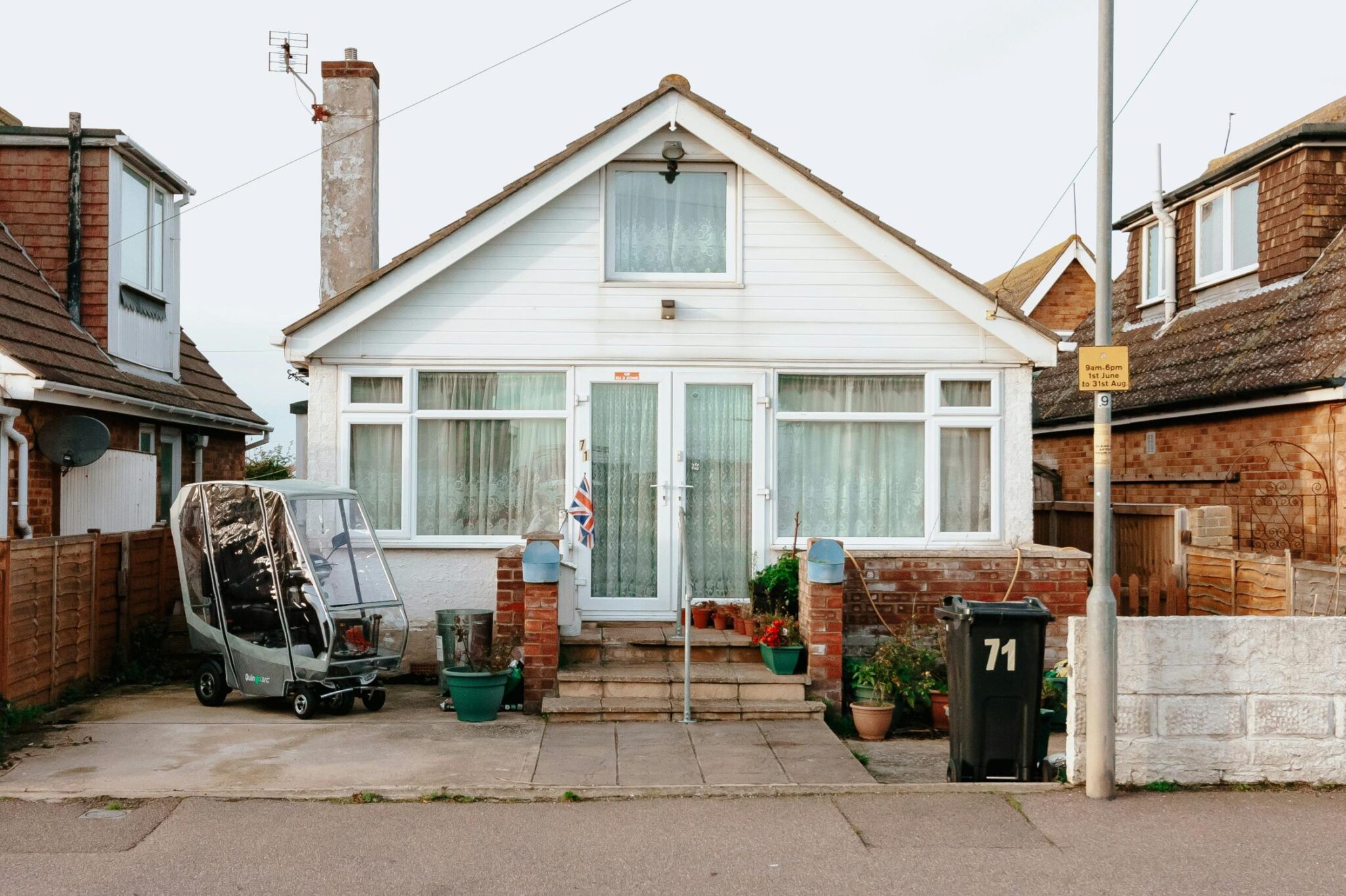 A bungalow in the UK with white cladding and a small front drive