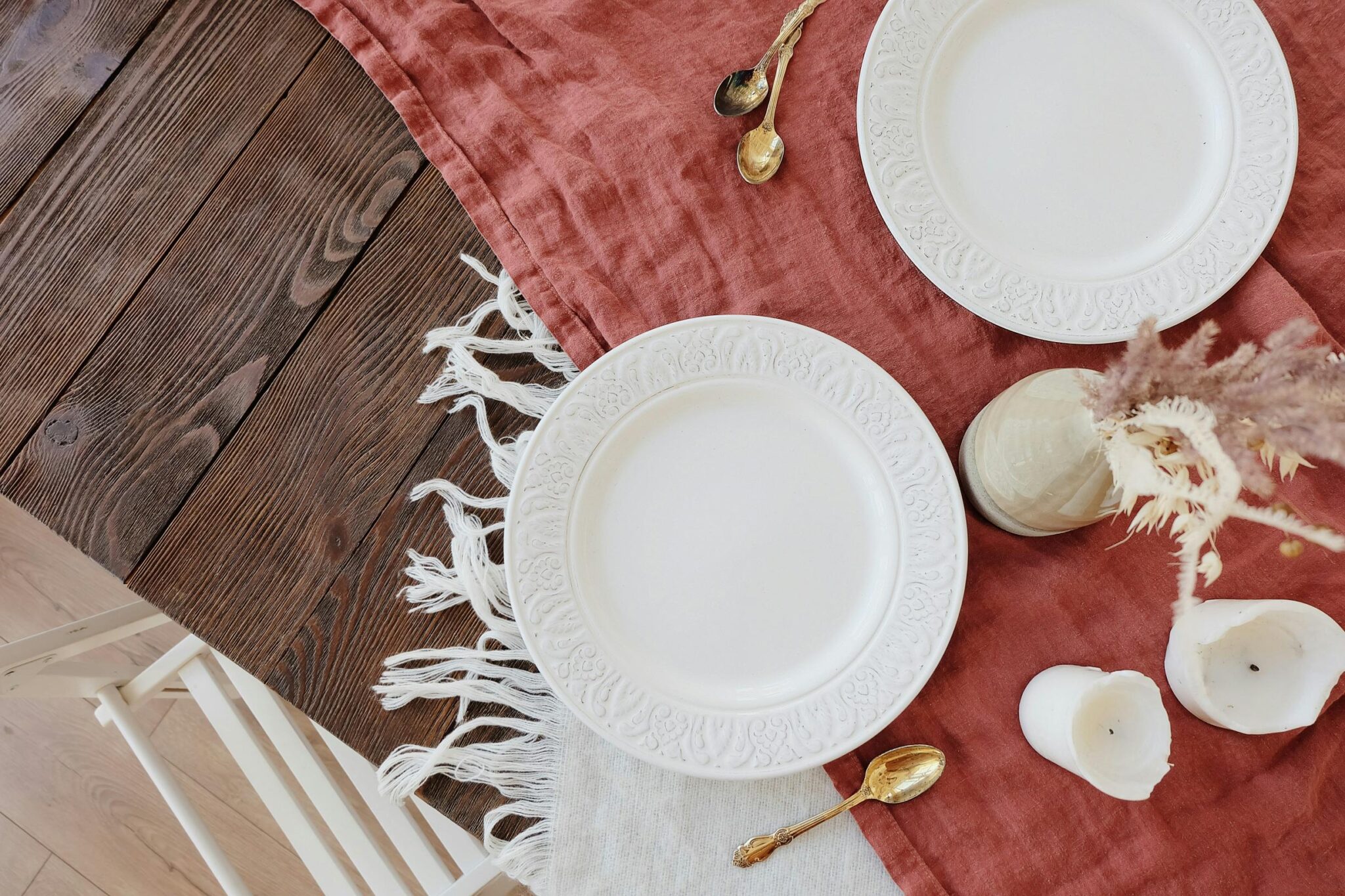 Two porcelain white plates laid on a table covered in a runner