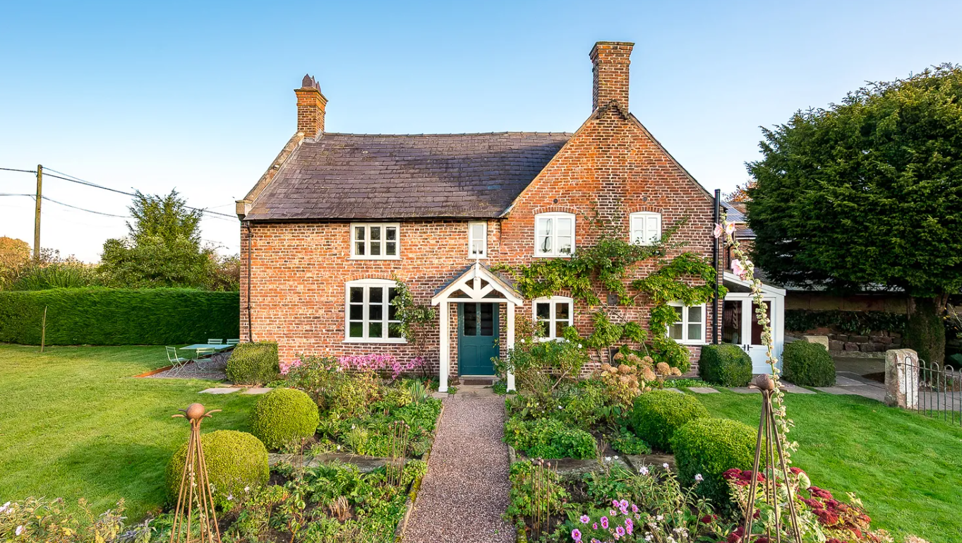 The exterior o Wheelwrights Cottage on a beautiful sunny day with blue sky