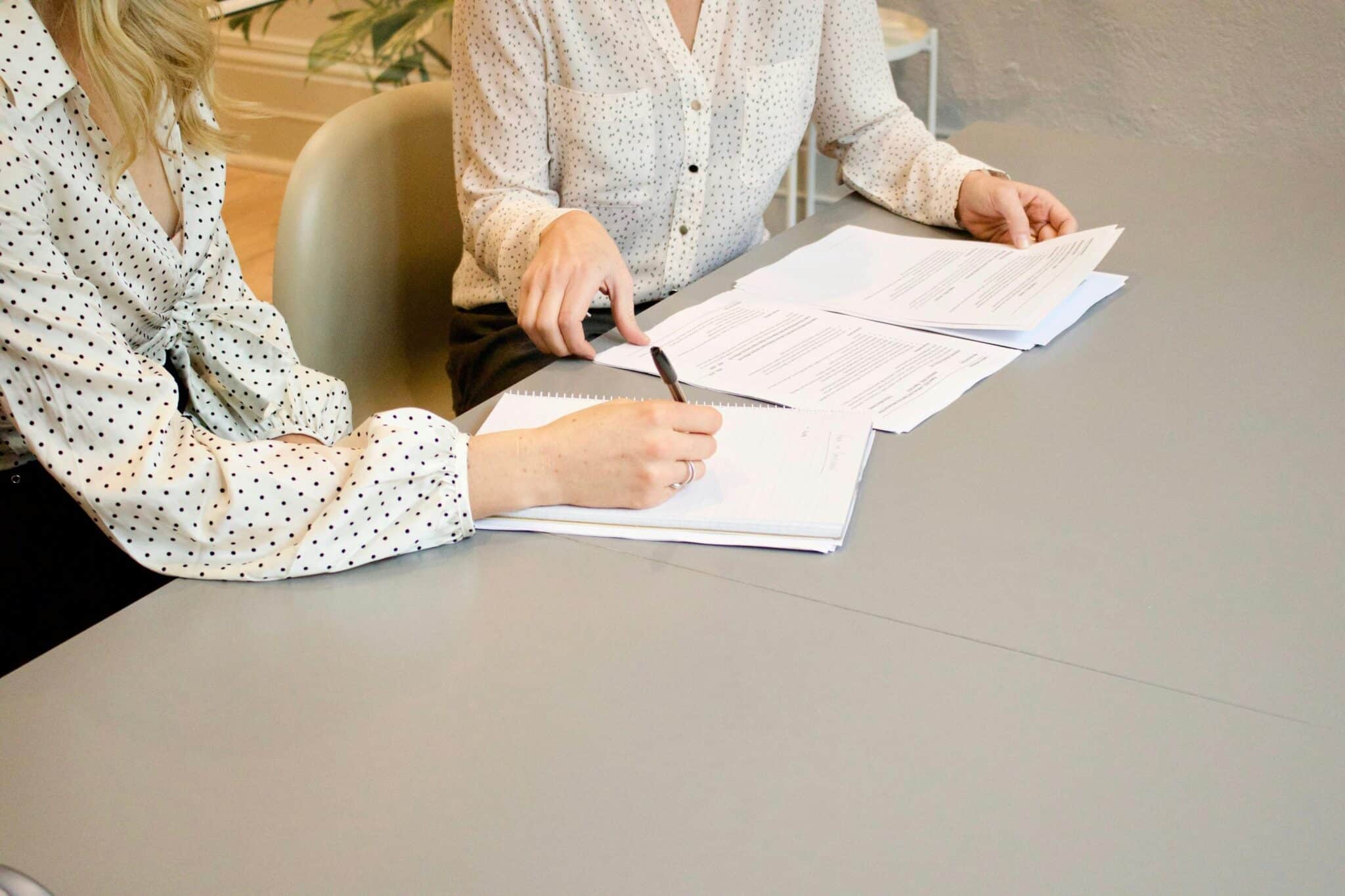 Two women signing a home buying contract
