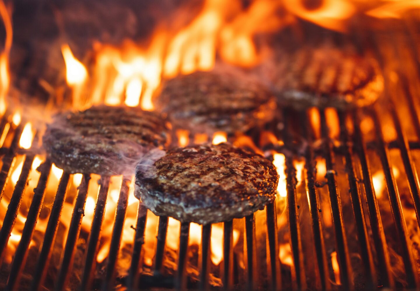 Burgers cooking on a high-heat charcoal bbq