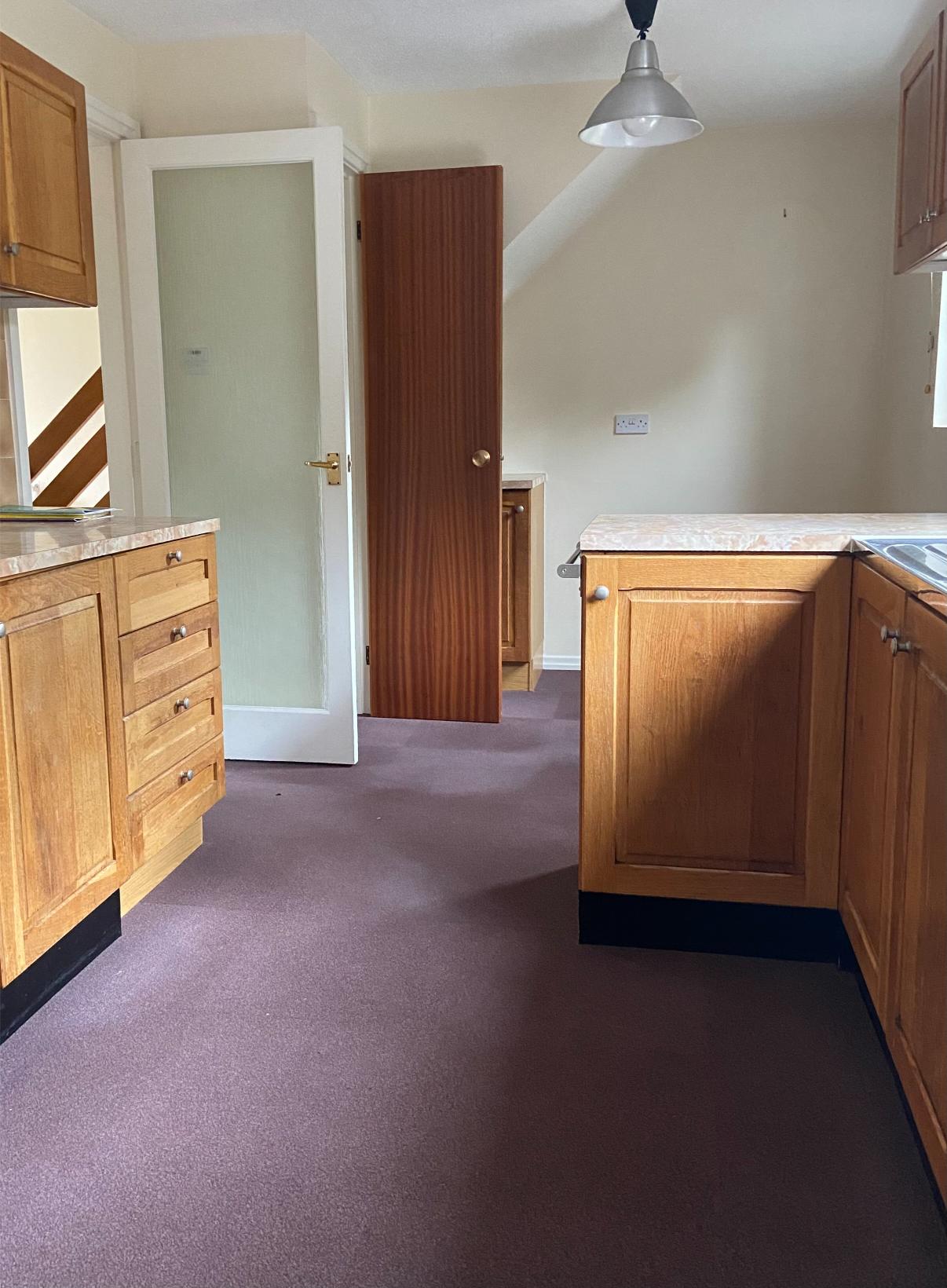 The kitchen before we painted it with red carpet tiles on the floor, brown cabinets and magnolia walls